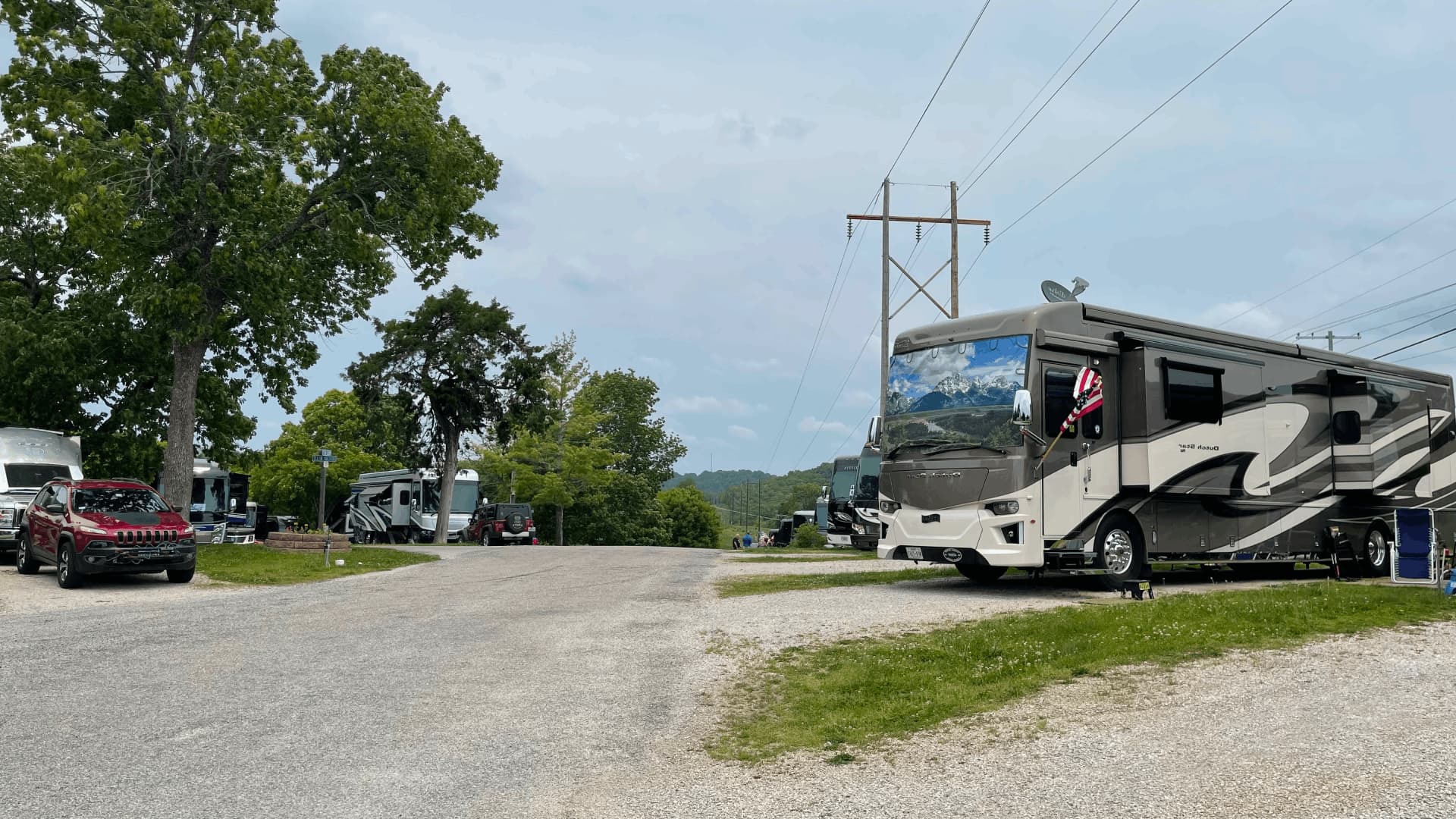 A large white RV is parked on a gravel road
