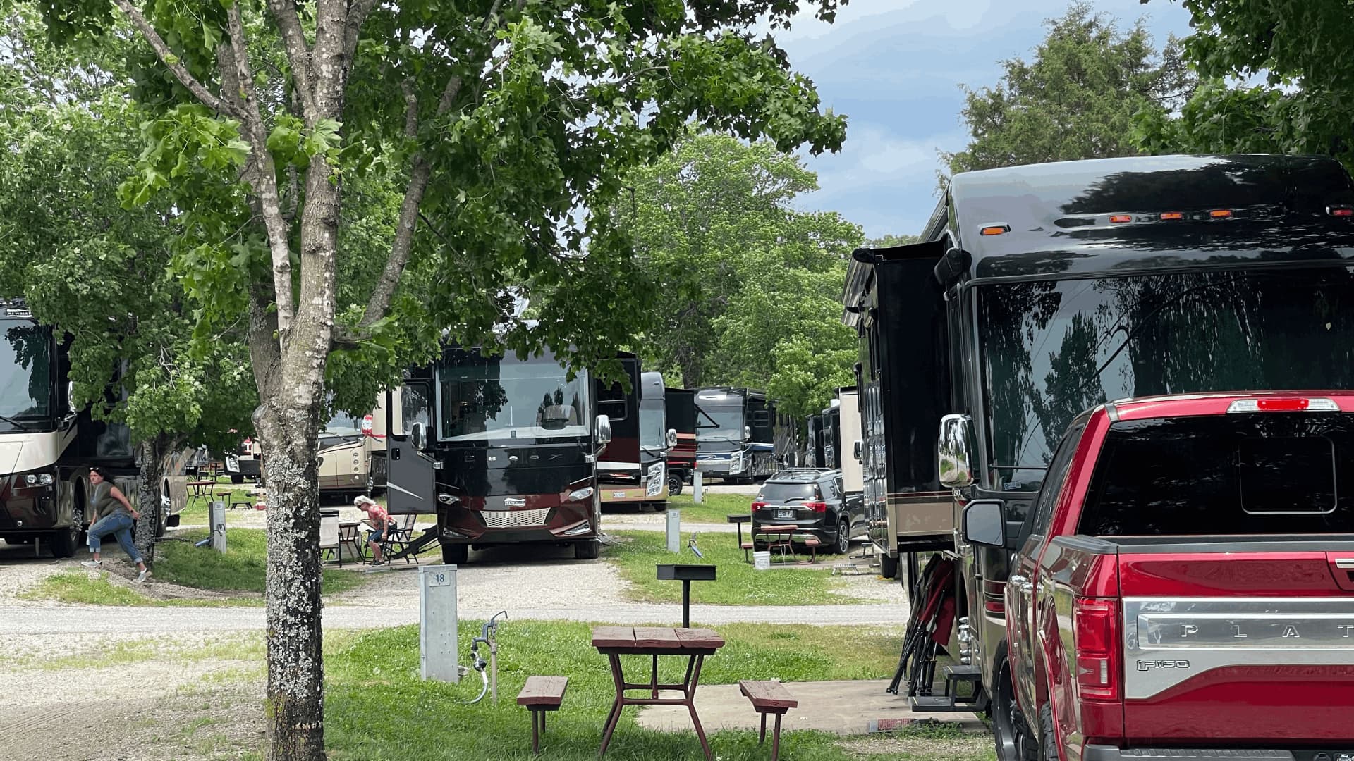 A park with several motor homes and cars parked in a lot