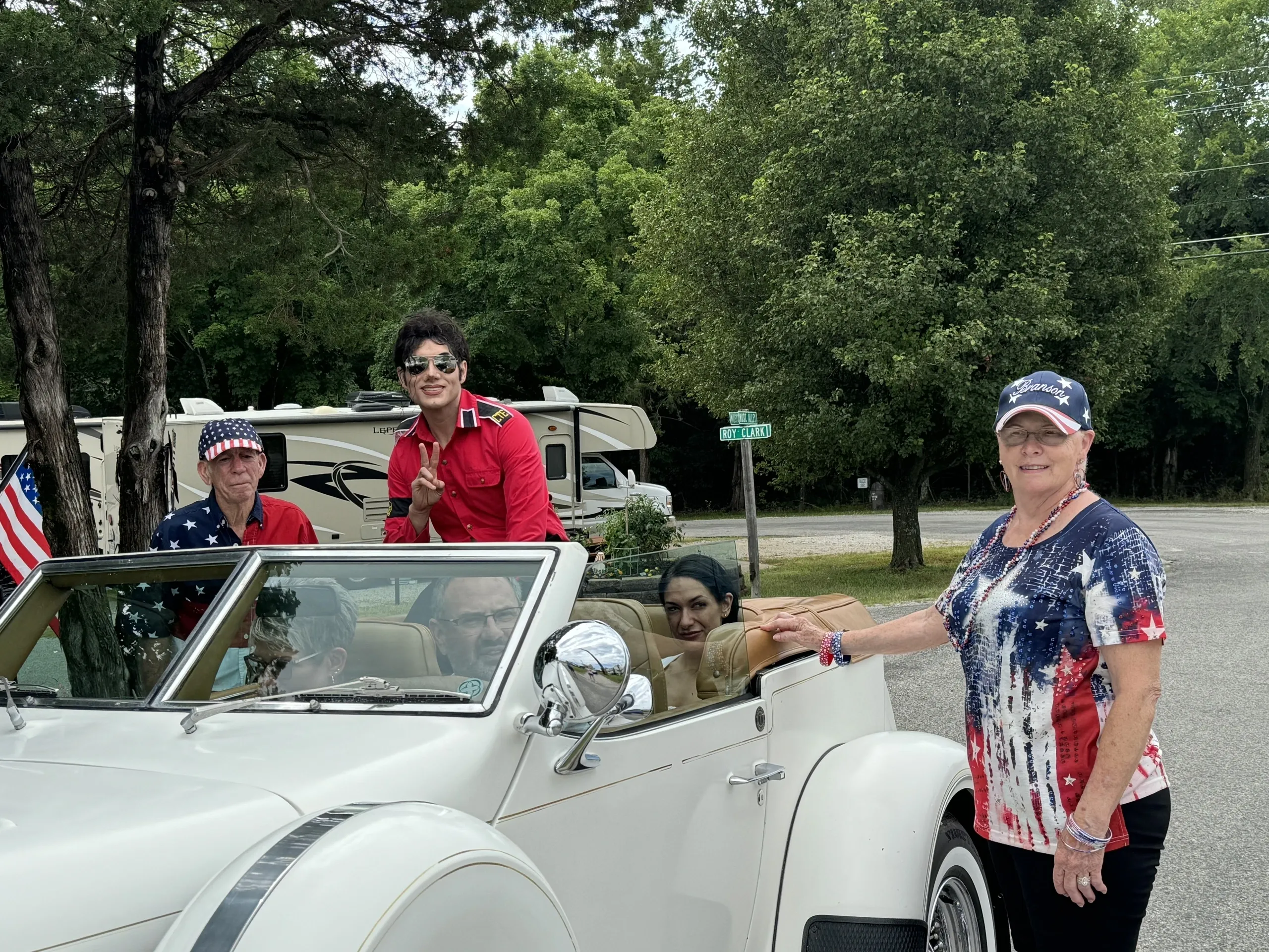 A white convertible car with a group of people in it