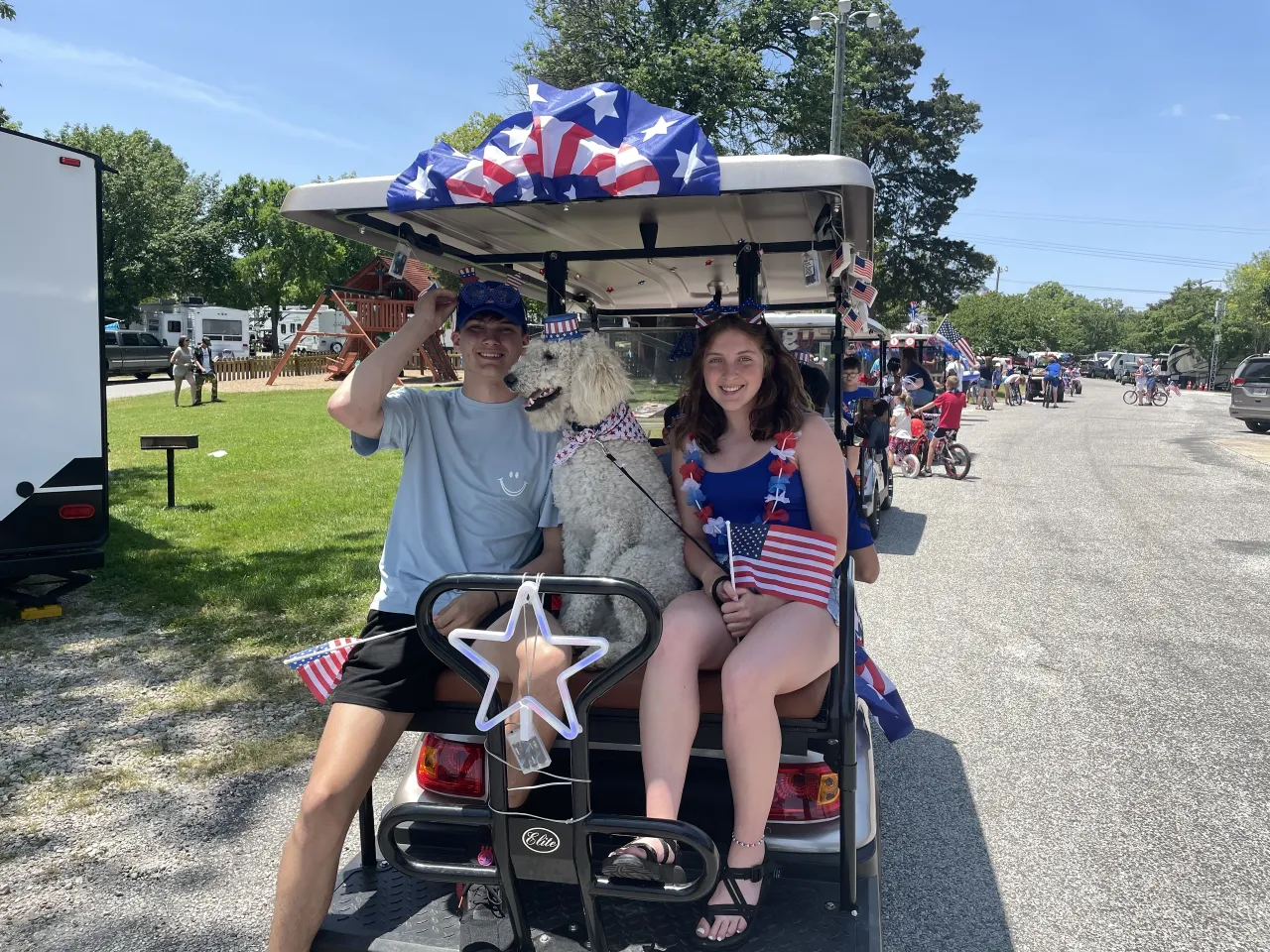 A man and a woman are sitting in a golf cart with an American flag on the back