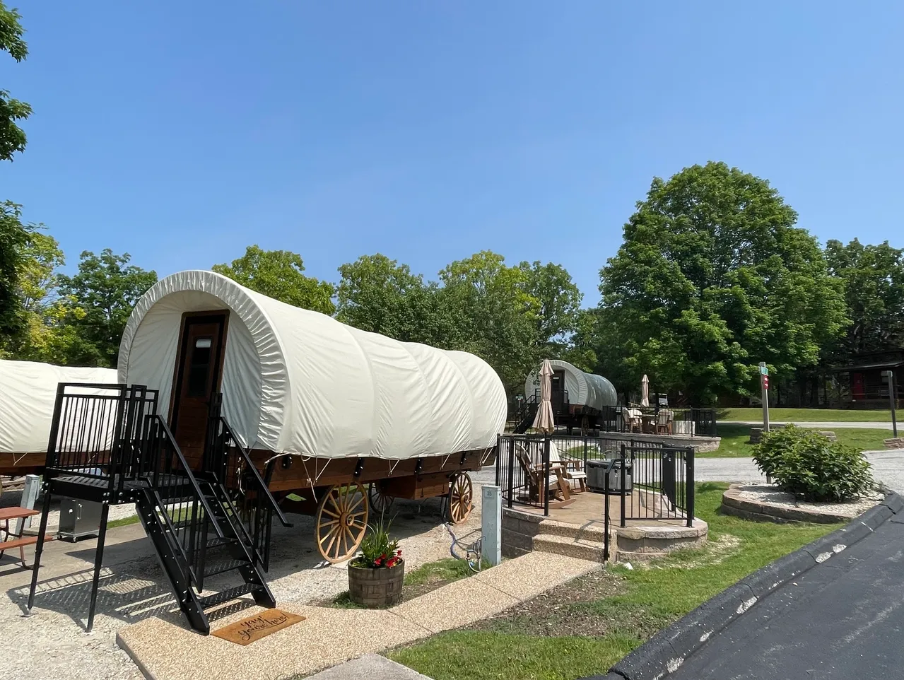 A wagon with a white cover is parked on a gravel driveway