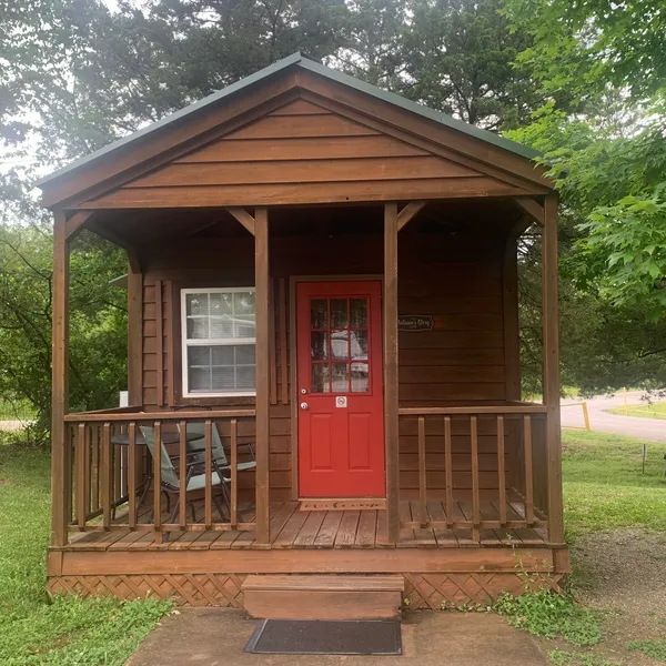 A small cabin with a red door and a brown roof
